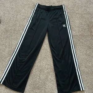 Svarta byxor från Adidas - Snygga svarta byxor från Adidas med de klassiska tre ränderna längs sidorna. Byxorna är lågmidjade, jag skulle gärna haft kvar de men tyvärr så är de för små för mig. Adidas-loggan är broderad på framsidan. Original pris(nya) är ca 800kr🙏🏼