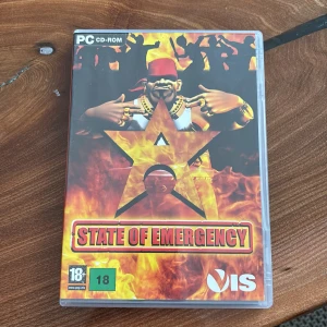 State of Emergency PC-spel - Säljer PC-spelet 'State of Emergency' från VIS. Innehåller originalförpackning, manual och CD-ROM. Spelet är märkt för 18+ och har en actionfylld design med eld och en stjärna på omslaget. Perfekt för dig som gillar intensiva spelupplevelser!