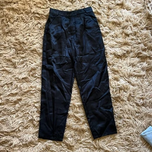 Svarta satinbyxor - Eleganta svarta byxor i satin och slutar några cm ovanför fotknölen.