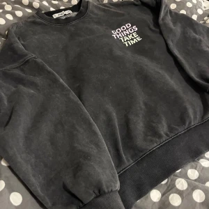 Svart sweatshirt med tryck - Säljer en svart sweatshirt med texten 'GOOD THINGS TAKE TIME' i pastellfärger på bröstet. Tröjan har långa ärmar och ribbade muddar vid ärmslut och nederkant. Perfekt för en avslappnad stil.