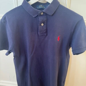 Blå pikétröja från Ralph Lauren - Klassisk raffepiké i bra skick. Storlek M