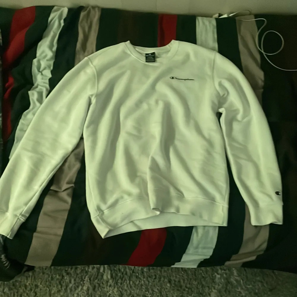 Säljer en stilren vit sweatshirt från Champion med deras klassiska logga på bröstet. Tröjan har långa ärmar och en bekväm passform, perfekt för en avslappnad stil. Passar bra till både jeans och träningsbyxor. 🏷️. Neuletakit & Villapaidat.