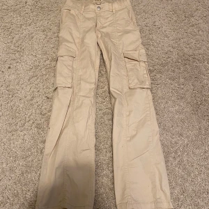 Beige cargobyxor från Lindex - Säljer ett par beige cargobyxor från Lindex med flera praktiska fickor och knappstängning. 🤩
