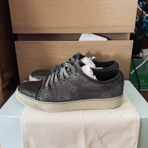  Lanvins  - Snygga grå sneakers från Lanvin med en stilren design. Skorna har en kombination av mocka och skinn, med en glansig tå och snörning framtill. Perfekta för en casual look med en touch av lyx strlk 42 passar även 41 skick 7,5/10 då sulan är lite sliten