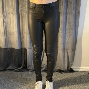 Svarta skinnbyxor byxor från D-XEL - Snygga svarta skinnbyxor byxor från D-XEL. De är midwaist. Byxorna har både fram- och bakfickor samt en dragkedja och knapp framtill. Modellen är 167cm lång