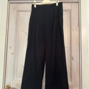 Svarta kostymbyxor från Gina Tricot - Eleganta svarta kostymbyxor från Gina Tricot i storlek XS Petie. Byxorna har en hög midja och en rak passform som ger en stilren look. Perfekta för både vardagen och festligheter. Endast använt fåtal gånger.