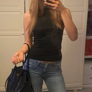 Svart ärmlös topp - Snygg svart ärmlös topp med tight passform. Perfekt för en stilren look. Passar bra till jeans eller kjol.