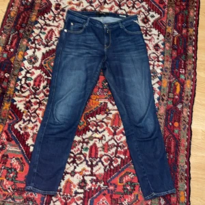 Blå jeans från Replay - Snygga blå jeans från Replay med klassisk femficksdesign och gylf. Perfekta för en avslappnad stil. Märkesdetaljer på baksidan ger en extra touch. Bra skick, inga defekter. Säljs nu för endast 449kr!