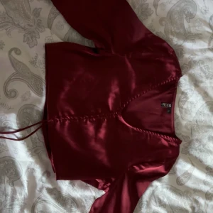 vinröd satinblus från pieces - snygg vinröd blus i satin från pieces med v-ringning och knytning framtill. blusen har långa ärmar och är i storlek xs / s                          pris går att diskuteras!