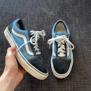  Vans skor - Säljer ett par klassiska Vans sneakers i blått och svart med vit sula och snörning. Skorna är knappt använda är i superfint skick. Perfekta för en avslappnad stil. Hör av dig om du har några funderingar.