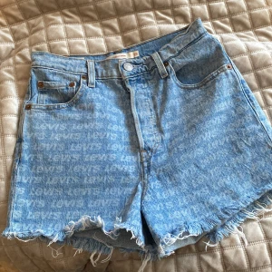 Blå jeansshorts från Levi's - Säljer ett par snygga blå jeansshorts från Levi's med fransiga kanter och hög midja. Shortsen har ett subtilt mönster och klassiska femficksdesign. Perfekta för en avslappnad sommarlook! 🌞