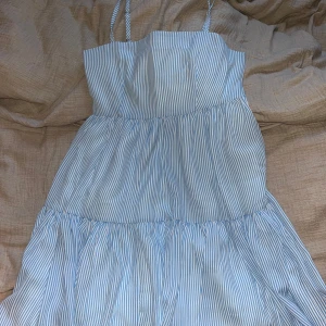 Blå- och vitrandig klänning från Lisa & Lena för NA-KD - Säljer en söt blå- och vitrandig klänning från Lisa & Lena för NA-KD. Klänningen har smala axelband och en luftig passform med volanger. Perfekt för varma sommardagar! 💙