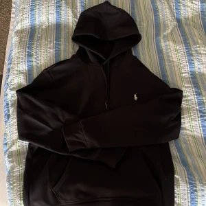 Svart hoodie från Polo Ralph Lauren - Säljer en stilren svart hoodie från Polo Ralph Lauren. Tröjan är använd ett fåtal gånger och är i utmärkt skick!