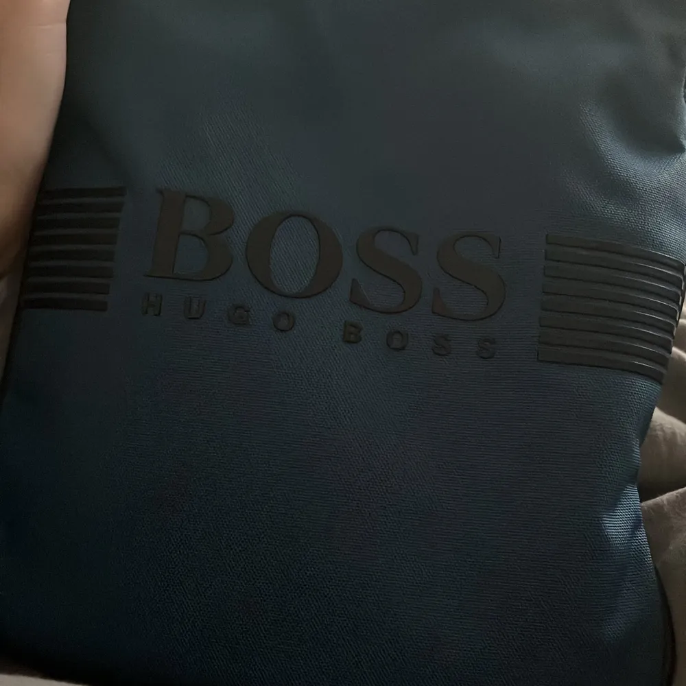 Snygg svart axelväska från Hugo Boss med stilren design och justerbar axelrem. Passar perfekt till sommaren . Laukut & Käsilaukut.