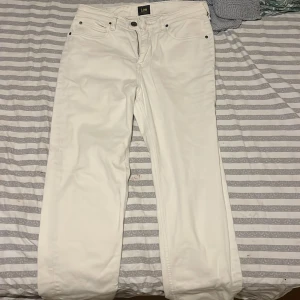 Vita jeans från Lee - Säljer ett par stilrena vita jeans från Lee. De har en klassisk femficksdesign och knappgylf. Perfekta för en fräsch och modern look. Passar till många olika stilar och tillfällen.