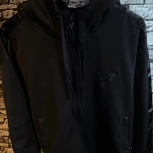 Svart hoodie från Dolce & Gabbana - Snygg svart hoodie från Dolce & Gabbana med broderad logotyp på bröstet. Den har dragkedja framtill och justerbar huva med snören. Perfekt för en stilren look.👀 helt ny testad en gång.köpt på Farfetch säljer för den va för stor kom dm för mer info 💯kvitto och tags finns kvar 
