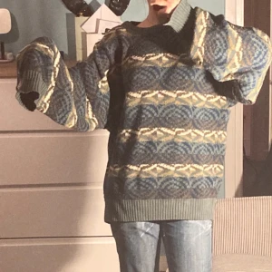 Mönstrad stickad tröja i blå och beige - Säljer en mysig stickad tröja med ett unikt mönster i blått och beige. Tröjan har långa ärmar och en ribbad kant vid ärmslut och nederkant. Perfekt för kyliga dagar!