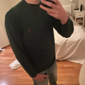 Mörkgrön tröja från Ralph Lauren 70% ull! - Säljer en stilren mörkgrön tröja från Ralph Lauren med det klassiska röda logotypbroderiet på bröstet. Tröjan har långa ärmar och en rund halsringning. Tröjan är i 70% ull vilket gör den riktigt skön! Storleken är M. Skicket på tröjan är bra! Vid fler frågor eller andra funderingar är det bara att skriva🙌