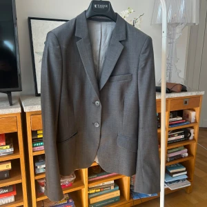 Grå kavaj från Tiger Of Sweden - Grå klassisk kavaj i 100% ull från Tiger Of Sweden. Den är inte för varm och i riktigt bra kvalité. Figursydd passform. Storlek 38 men passar även 36.