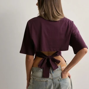 Vinröd kortärmad topp med knyt - Snygg vinröd topp med korta ärmar och knytning i ryggen. Perfekt för en avslappnad stil med en twist. Passar bra till jeans eller kjol.