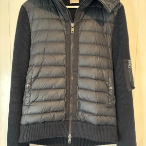 Moncler Cardigan  - Snygg och stilren cardigan från Moncler med quiltad framsida och stickade ärmar. Den är storlek L men passar om man har M i andra kläder. Toppskick 9/10 och väldigt sparsamt använd. En modell som är väldigt svår att få tag på. Funkar perfekt på vår och höst men även sommarkvällar! Hämtas i Täby eller skickas säkert. Nypris: 8500+. Mitt pris: 3499 kr