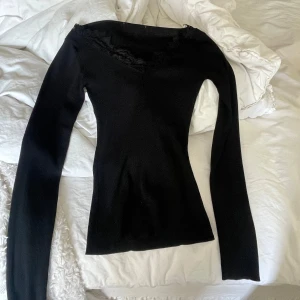 Svart ribbad topp med spetsdetaljer - Säljer svart ribbad topp med långa ärmar och spets vid halsen