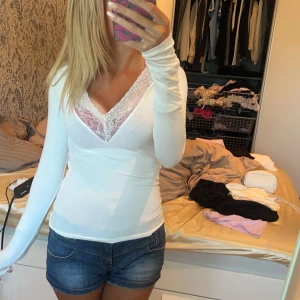 Vit långärmad topp med spetsdetaljer - Snygg vit långärmad topp med v-ringning och spetsdetaljer.  Passar bra till allt o den är knappt använd