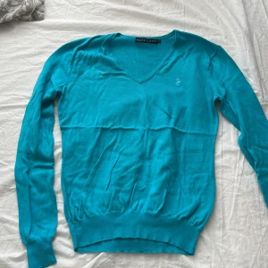 Turkos tröja från Secondhand  - Säljer en snygg turkos tröja från Ralph Lauren med v-ringning. Tröjan har långa ärmar och ribbade muddar vid ärmslut och nederkant. Perfekt för en stilren look.