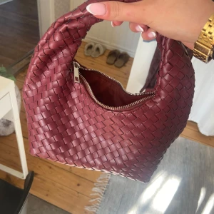 Vinröd flätad handväska - Säljer en snygg vinröd handväska med flätat mönster. 