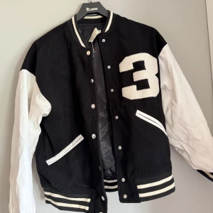 Svart och vit bomberjacka från NLY Trend - Storlek 32 men stor i storleken så mer som en S/M. Använt skick samt en fläck som syns på ärmen på bild 3. Tvättas innan skickas naturligtvis.