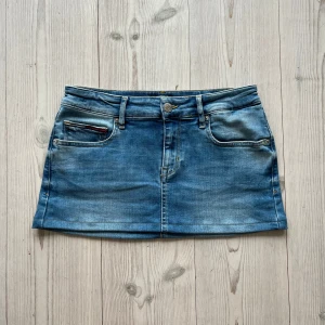 Blå lågmidjad jeanskjol från Tommy Hilfiger  - Ljusblå lågmidjad jeanskjol från Tommy Hilfiger som jag har sytt upp från en längre kjol i storlek 29. Fint skick. Tvärs över midjan är det 37 cm+ stretch och den är 28 cm lång. Passar S och M. Använd gärna köp nu!