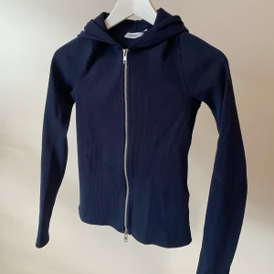 Tight ribbad hoodie med extra långa ärmar - Tight mörkblå luvtröja från Weekday med dragkedja som går att öppna från två håll. Den är ribbad och har extra långa ärmar - jättefin passform som funkar under alla jackor! Endast använd några enstaka  gånger.
