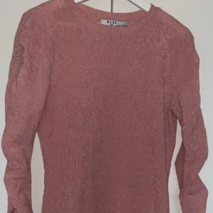 Rosa ribbad klänning från NA-KD - Säljer en snygg rosa ribbad klänning från NA-KD. Tröjan har långa ärmar och en bekväm passform, perfekt för både vardag och speciella tillfällen. Den är tillverkad i ett mjukt material som känns skönt mot huden.