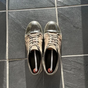 Grå Lanvins med mockadetaljer - Schyssta grå Lanvins med en kombination av mocka och glansiga detaljer på tån. Skorna har snörning och en stilren design som passar perfekt för en avslappnad look. Perfekta för dig som vill ha något unikt och stilrent. 