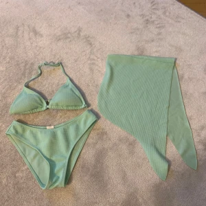Mintgrön bikini med kjol - Snygg mintgrön bikini med trekantsöverdel och matchande kjol. Bikinin har knytband i nacken och en ribbad textur som ger en trendig look. Perfekt för sommarens stranddagar!