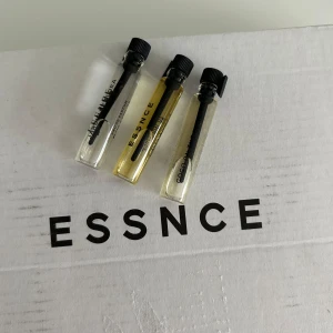 Parfymprover från Essnce - Tre parfymprover från Essnce: 'Coco on the Beach', 'I Am Vanilla' och 'Jardin de Flora'. Varje flaska är liten och smidig, perfekt för att testa nya dofter. Flaskorna har svarta lock och transparent design som visar vätskans färg.