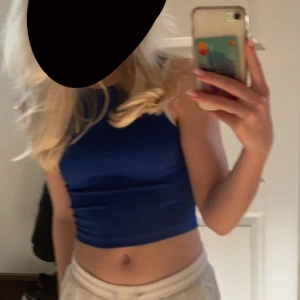 Blå croppad linnetopp - Snygg blå croppad linnetopp med rund halsringning. Perfekt för varma dagar eller som en del av en lager-på-lager-look. Enkel och stilren design som passar till det mesta.