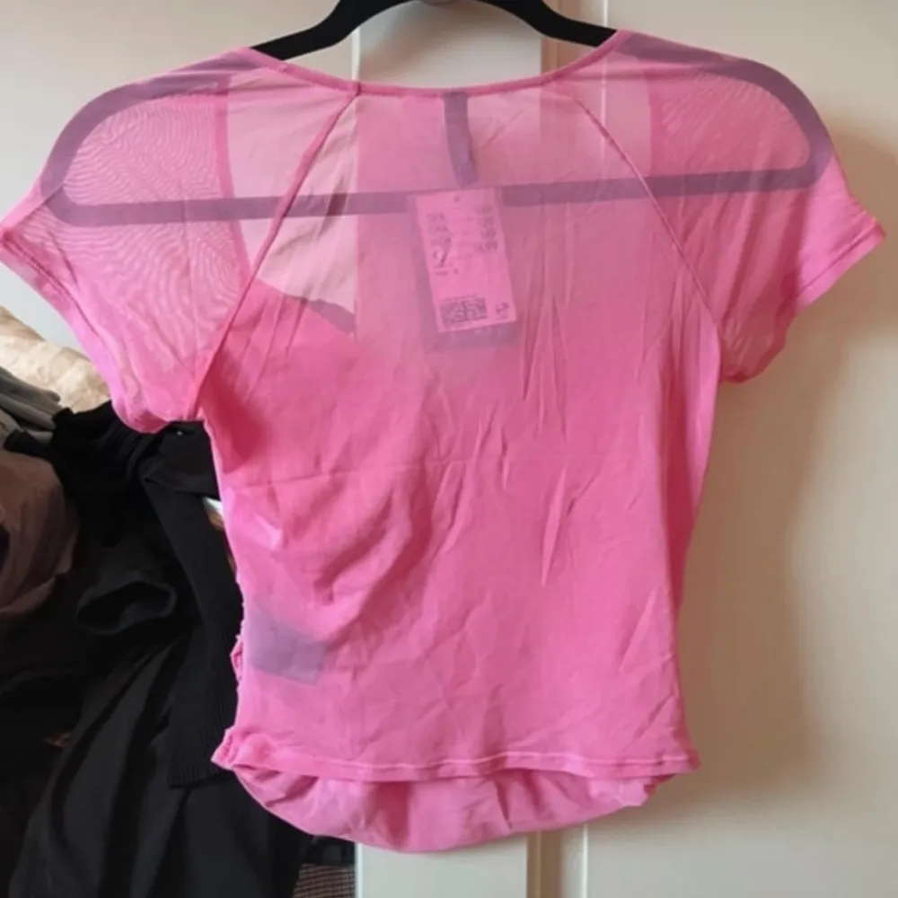 Säljer en rosa mesh topp från H&M Divided i storlek S Toppen har korta ärmar och en snygg rynkad detalj vid bysten. Tillverkad av 95% återvunnen polyester, perfekt för en trendig look.. Yläosat.