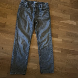 Grå jeans - Säljer ett par grå jeansbyxor från Zara. De har en klassisk femficksdesign och stängs med dragkedja och knapp. Perfekta för en avslappnad stil. Ser nya ut förutom den bruna lappen där bak som är sönder.