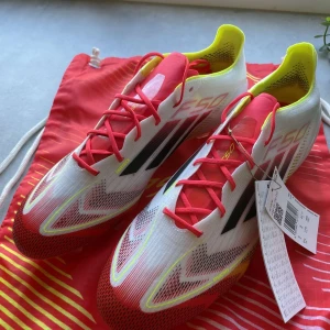 Adidas F50 Elite FG fotbollsskor  - Snygga Adidas F50 Elite FG fotbollsskor i vitt med svarta och gula detaljer. Helt nya aldrig använda endast testade nypris 3100 kr mitt pris 2500 kr Kan gå ner i pris vid snabb affär!