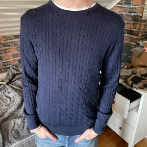 Kabelstickad tröja från Stenströms - Säljer en stilren mörkblå kabelstickad tröja med rund halsringning från Stenströms. Tröjan har långa ärmar och ribbade muddar vid ärmslut och nederkant. Perfekt för lite kyligare dagar. Nypris är 2000