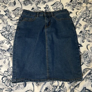 Jeanskjol från Vero Moda - Använt en gång. Snygg jeanskjol från Vero Moda i klassisk blå denim. Kjolen har en normal passform med femficksdesign och bälteshällor. Kjolen slutat vanför knäna. Stretchig. 