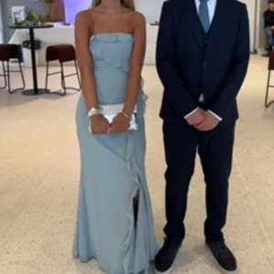 Ljusblå/ sage green axelbandslös klänning - Elegant ljusblå axelbandslös klänning med volangdetaljer och slits framtill. Perfekt för bal! Från Lulus, köpt för cirka 1200! 