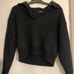 Svart stickad tröja med krage - Säljer en svart stickad tröja med en unik krage och v-ringning. Tröjan har långa ärmar och en ribbad struktur som ger en stilren look. Perfekt för kyligare dagar.