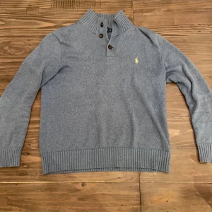  tröja från Polo Ralph Lauren - Säljer en stilren  tröja från Polo Ralph Lauren i 100% bomull. Tröjan har en hög krage med knappar och det ikoniska broderade logotypen på bröstet. Perfekt för en avslappnad men elegant look.