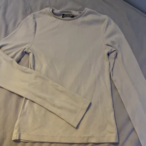 Ljusribbad långärmad tröja - Enkel och stilren ljus långärmad tröja med ribbad struktur. Tröjan har rund halsringning och är figurnära utan att vara tight. Perfekt att styla med jeans eller kjol för en clean look.