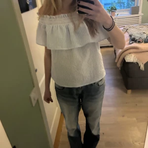Randig offshoulder topp  - Ljusblå och vitrandig offshoulder topp med volang! Köpt i Prag, storleken är L men den passar som S och M🩷