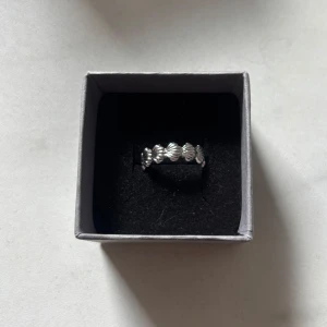 Snygg silverring med snäckformad design - Gullig silverfärgad ring med snäckformade detaljer runt hela ringen. Ringen är öppen baktill vilket gör den justerbar. Vet inte om den rostar eller om man blir grön av den. Aldrig använd. OBS! Asken medföljer ej! Läs gärna min bio💕obs! Skriv innan köp, säljer på fler ställen!!