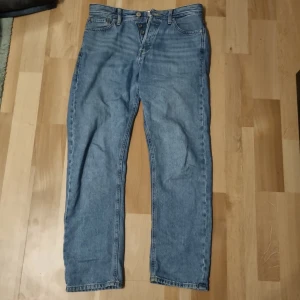 Blå jeans från Jack & Jones 29/30 chris - Klassiska blå jeans från Jack & Jones i relaxed modell. Jeansen har knappgylf och snyggt läderpatch bak i midjan.