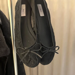 Svarta ballerinaskor med spets  - Snygga svarta ballerinaskor från Nelly med spetsdetaljer och söt rosett framtill. Skorna har rund tå och platt sula, vilket gör dem både stilrena och bekväma. Använda upp mot 3 gånger, så extremt bra skick.💕